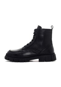 Botín alto de cuero negro con suela de goma gruesa y chunky y cordones en la parte delantera, diseñado para una moda resistente y durabilidad.
