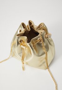 Gouden metallic bucketbag met eenGathered top, voorzien van gouden hardware-accenten en een kettingstrap. Gladde textuur en touwsluiting.