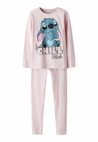 Ensemble haut à manches longues et pantalon rose avec un personnage de dessin animé Stitch assis et le texte "Just Chill Stitch" sur le haut.
