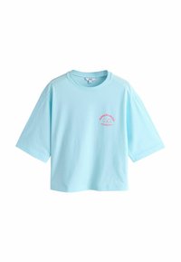 Svetlo modra bombažna majica s kratkimi rokavi z udobnim krojem. Ima roza grafični motiv na prsih in okrogel izrez.