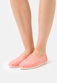 Rosa Stoff-Slipper mit strukturierten Oberflächen, runder Zehenpartie, elastischen Seitenpaneelen und einer weißen Gummisohle.