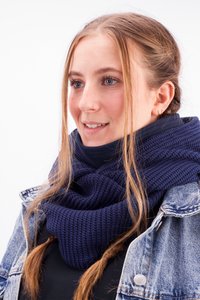 Navy blue knitted scarf with a textured pattern, worn layered over a black top, complementing a denim jacket.
