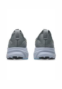 Grå sportskor med ett texturerat övre material, stödjande hälkappa och en tjock vit mellansula. Svart mönster och blå detaljer på sulan.