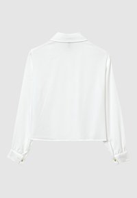 Weiße Bluse mit Kragen und langen Ärmeln, ausgestattet mit geknöpften Manschetten und einer glatten Textur. Kurze Länge, klares Design, minimalistischer Stil.