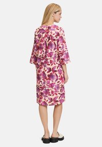 Floral Kleid in hellem Creme mit lila und rosa Mustern, dreiviertel Ärmel, lockere Passform, knielang, aus leichtem Stoff gefertigt.