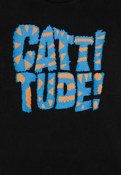 Camiseta negra con un gráfico textil vibrante en azul y naranja que dice "¡CATTITUDE!" El texto tiene un diseño texturizado y juguetón con acentos triangulares.