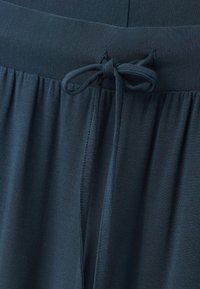 Dunkelblau-grüne Stoffhose mit einer Kordelzugtalie und einer strukturierten Oberfläche. Das weiche, leichte Material sorgt für Komfort und Flexibilität.