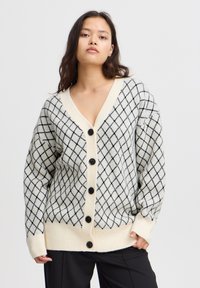 Cardigan lavorato a maglia in crema con un motivo a diamante nero, caratterizzato da un profondo scollo a V, cinque bottoni neri e polsini e orlo a coste.