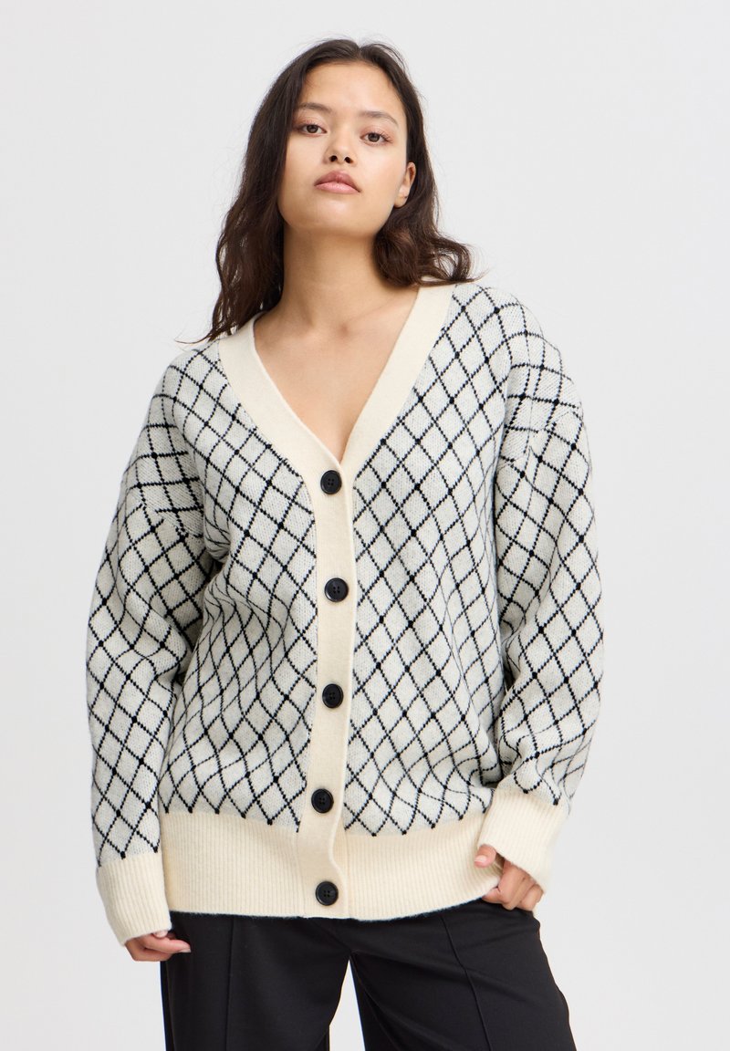 Cardigan lavorato a maglia in crema con un motivo a diamante nero, caratterizzato da un profondo scollo a V, cinque bottoni neri e polsini e orlo a coste.