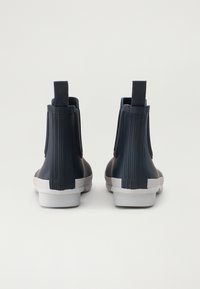 Botas de lluvia de goma en azul marino oscuro, con estrías verticales, tiradores y una suela blanca. Textura suave con un diseño de punta redondeada.