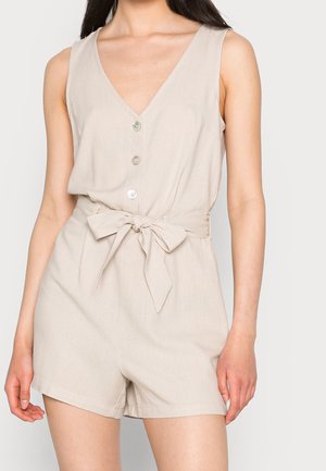 Beige ærmeløs jumpsuit med V-hals, knapper foran og bindebælte i taljen. Fremstillet af letvægtsstof med en glat tekstur.