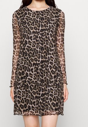 Femme portant une mini-robe à manches longues semi-transparente avec un motif léopard et un col rond.