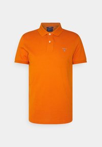 Pomarańczowa koszulka polo z bawełny, z klasycznym kołnierzykiem, dwu guzikowym zapięciem oraz haftowanym logo na klatce piersiowej. Krótkie rękawy.