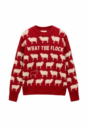 Červený pletený sveter s bielymi vzormi oviec a textom "ČO TO PLOCHÁ" na hrudi, pričom medzi bielymi ovcami je jedna čierna ovca.