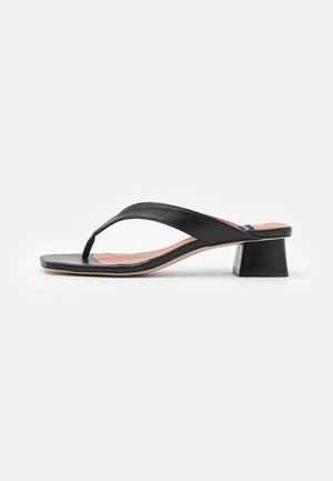 Sort læder hæl-sandal med thong-rem, firkantet tå og lav blokhæl på hvid baggrund.