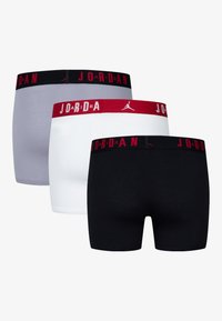 Drei Paar Boxershorts in Grau, Weiß und Schwarz. Die elastischen Bündchen sind mit "JORDAN" und einem Logo in Rot und Schwarz versehen. Glatte Stoffstruktur.