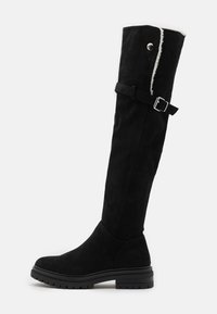 Czarne zamszowe kozaki za kolano z płaską gumową podeszwą, z bocznym paskiem i klamrą, miękkie białe wykończenie na górze.