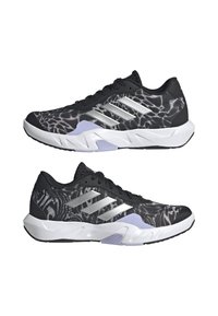 Sportliche Schuhe mit einem schwarzen und silbernen Design. Sie verfügen über ein strukturiertes Obermaterial, eine dicke weiße Zwischensohle und lila Akzente an der Sohle.