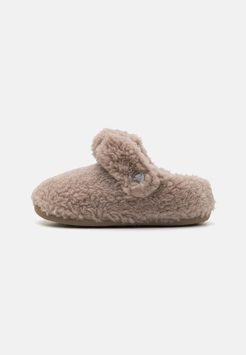 Luddig beige toffel med rund tå och ett justerbart spänne. Tillverkad av mjukt tyg med en texturerad, plyschyta, med en cirkulär logotypaccent.