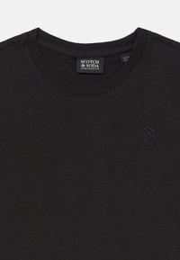Schwarzes Baumwoll-T-Shirt mit rundem Halsausschnitt. Mit einem tonal gestickten Logo auf der Brust. Weiche Textur und normale Passform.