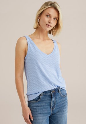 Lichtblauw mouwloos topje met een V-hals en subtiel chevronpatroon, gemaakt van zachte stof, gecombineerd met hooggetailleerde blauwe jeans.