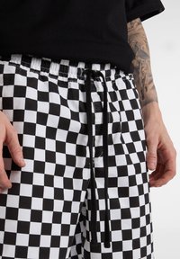 Sort-hvide ternede shorts med elastisk talje og sort snor, der har en glat stoftekstur og et afslappet design.