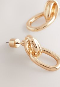 Gold-tone metal earrings featuring a linked, oval design with a textured finish and a stud post for fastening.