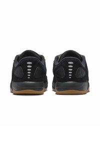 Baskets en suede noir avec une tige texturée, une semelle en caoutchouc gum et des détails distincts au niveau du talon, incluant des accents gris et un design strié.