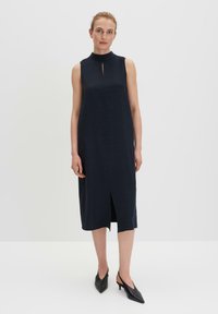 Marineblaues ärmelloses Kleid mit hohem Kragen, ausgestattet mit einem Schlitz vorne und einer geraden Silhouette, gefertigt aus einem glatten, fließenden Stoff.