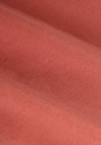 Tissu texturé d'une teinte corail chaude, avec une surface lisse et légèrement brillante, présentant des variations subtiles de couleur et de profondeur.