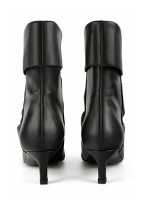 Stivaletti in pelle nera con risvolti e tacchi a stiletto sottili, mostrati di spalle su uno sfondo bianco.