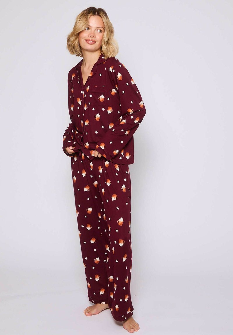 Conjunto de pijama burdeos que incluye una camiseta de botones con un bolsillo en el pecho y mangas largas, combinada con pantalones a juego, ambos decorados con un patrón de estrellas y naranjas.