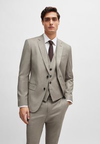 Lichtgrijs drie-delig kostuum met een notch lapel, voorzien van een button-up vest en een donkerbruine stropdas. Glad textuur, slim-fit ontwerp.