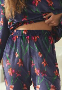 Lilleline pidžaamakomplekt tumelõhnavärvi taustal; sisaldab erksaid roosasid lilli ja rohelisi lehti, pehme kangas, elastne vöökoht, mugav lõige.