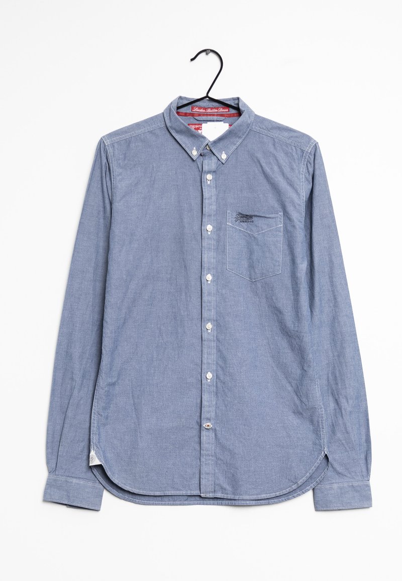 Vaaleansininen pitkähihainen nappikauluspaita, joka on valmistettu chambray-kankaasta. Paidassa on rintatasku ja pyöristetty helma, jossa on sivuhalkiot.