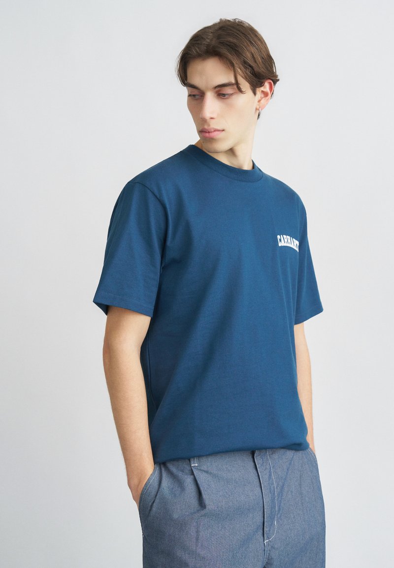 Μπλε ναυτικό βαμβακερό μπλουζάκι με στρογγυλή λαιμόκοψη και κοντά μανίκια, με λευκό τυπωμένο λογότυπο στο αριστερό στήθος.