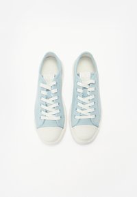 Scarpe da ginnastica in tela blu chiaro con suole e punte in gomma bianca. Presentano lacci bianchi e un design testurizzato sulla tomaia.