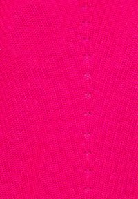 Jasně růžová pletená látka s texturovaným vzorem a malými dekorativními otvory běžícími vertikálně dolů uprostřed. Měkký a elastický materiál.
