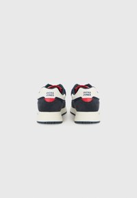 Marineblå og hvide sneakers med røde detaljer. Har ruskind, polstret krave og gummisål. Brandlogo på hælen.