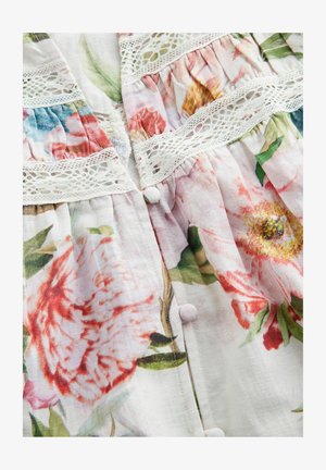 Tkanina s cvjetnim uzorkom koja sadrži ružičaste i crvene cvjetove na svijetloj pozadini. Ima bijelu čipkastu obrubu i male okrugle gumbe. Mekana tekstura.