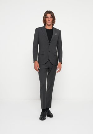 Gray suit with single-button blazer, matching slim trousers, and black shirt underneath. Smooth fabric with minimalistic design and no visible patterns.
