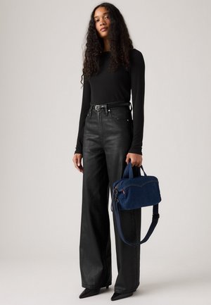 Black long-sleeve top and high-waisted, wide-leg black jeans. Blue denim handbag with short handles and a detachable shoulder strap.