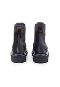 Stivali ankle neri in suede con tomaia in tessuto testurizzato, suola in gomma spessa e linguetta sul retro. Finitura liscia e dettagli di cucitura minimi.