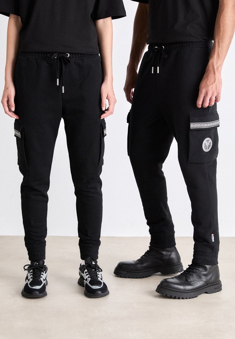 Zwarte sweatpants met elastische tailleband en trekkoord; voorzien van zijzakken; gestructureerde stof; gecombineerd met sportieve en casual schoenen.
