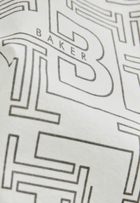 Biała tkanina z nadrukiem w geometryczne czarne linie oraz słowem "BAKER". Tekstura jest gładka i lekko rozciągliwa.