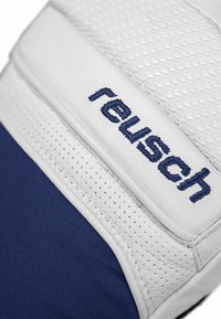 Guante de portero en blanco y azul marino con superficie de agarre texturizada, orificios de ventilación y bordado de la marca "reusch" en la correa.