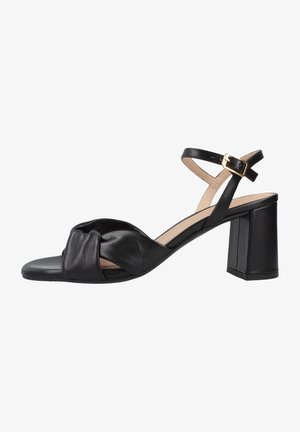 Sandaletto con tacco da donna in pelle nera, con cinturino frontale intrecciato, cinturino regolabile alla caviglia con fibbia dorata e tacco a blocco su sfondo bianco.