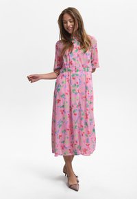 Rosa blommig klänning med korta ärmar, knappar framtill, insvängd midja, med abstrakta mönster i röda och gröna toner.