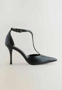 Zwarte hoge hak schoen met een spitse neus, gestructureerd faux leer, enkelband met een metalen gesp en een gebogen silhouet.