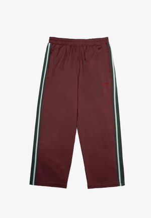 Pantaloni da tuta bordeaux con vita elastica, strisce laterali verdi e bianche, due tasche frontali e piccolo logo ricamato sulla coscia sinistra.